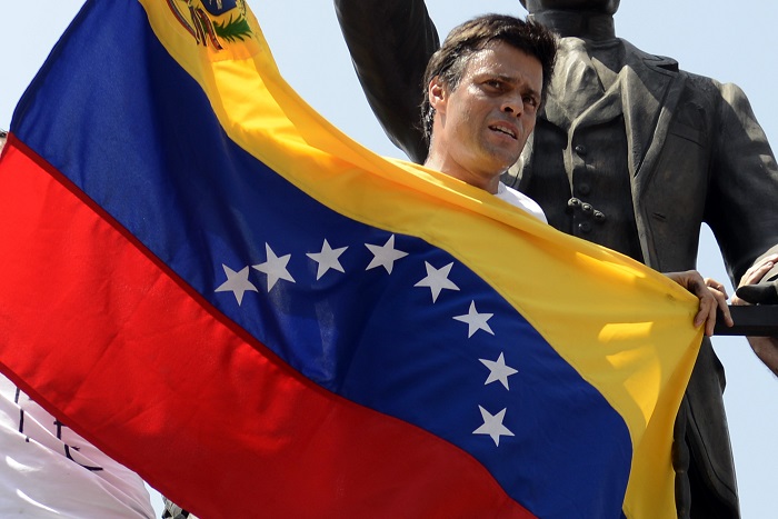 Leopoldo Lopez, an ardent opponent of Venezuela's socialist government facing an arrest warrant after President Nicolas Maduro ordered his arrest on charges of homicide and inciting violence, stands at the monument of Cuba's most important independence-era hero, Jose Marti, as he demonstrates with a national flag in Caracas before turning himself in to authorities, on February 18, 2014. Fugitive Venezuelan opposition leader Lopez, blamed by Maduro for violent clashes that left three people dead last week, appeared at an anti-government rally in eastern Caracas and quickly surrendered to the National Guard after delivering a brief speech. AFP PHOTO / LEO RAMIREZ
